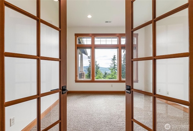 carpeted spare room with french doors, plenty of natural light, visible vents, and baseboards