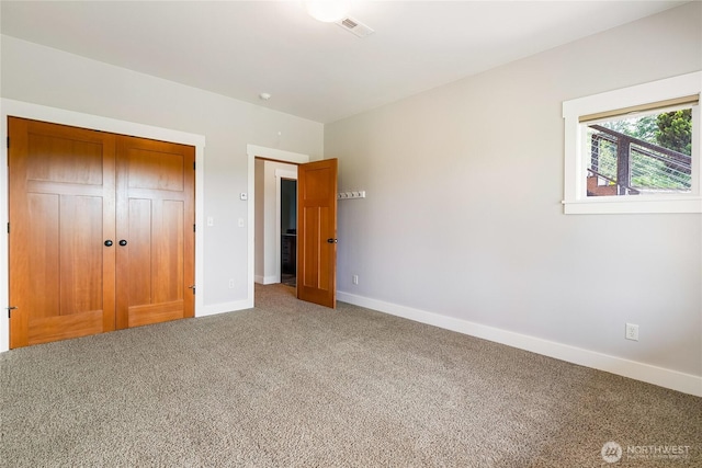 unfurnished bedroom featuring carpet floors, a closet, visible vents, and baseboards