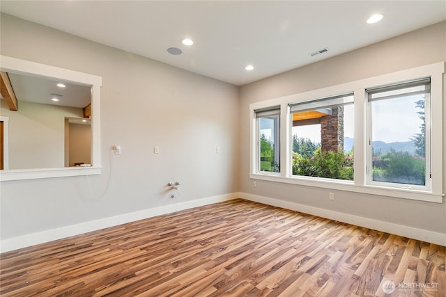 empty room with recessed lighting, wood finished floors, visible vents, and baseboards