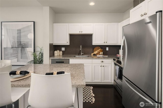 kitchen with a sink, decorative backsplash, appliances with stainless steel finishes, and white cabinets