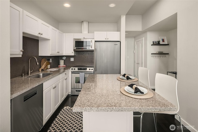 kitchen with a kitchen island, white cabinetry, stainless steel appliances, and a sink