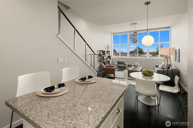 kitchen featuring light stone countertops, white cabinetry, a center island, and hanging light fixtures