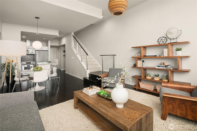 living room featuring stairway, baseboards, and wood finished floors