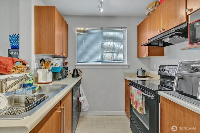 kitchen with black appliances, brown cabinetry, a sink, and under cabinet range hood