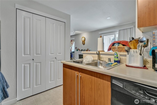 kitchen with dishwasher, light countertops, a peninsula, and a sink