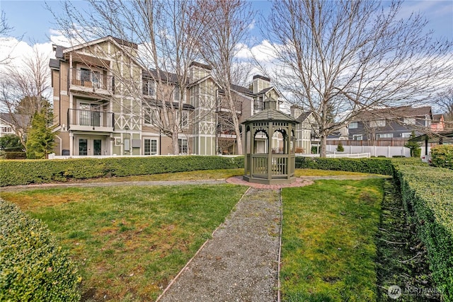 view of home's community with a lawn, a gazebo, and fence