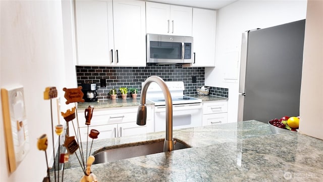 kitchen with stainless steel appliances, white cabinets, and decorative backsplash