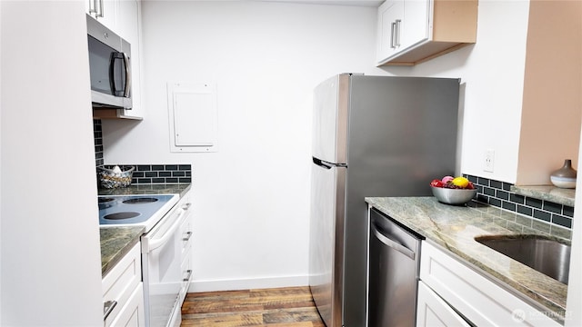 kitchen featuring stainless steel appliances, light stone counters, white cabinetry, and decorative backsplash