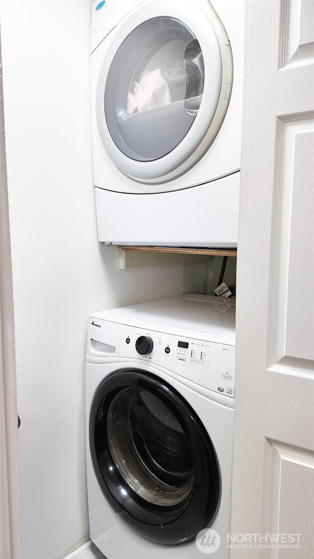 clothes washing area with stacked washer / dryer and laundry area