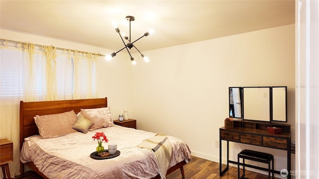 bedroom featuring baseboards, dark wood finished floors, and an inviting chandelier