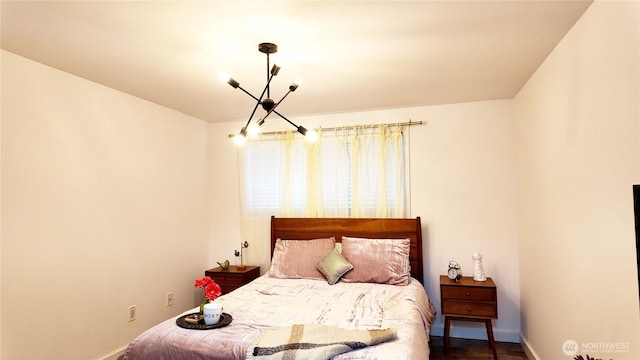 bedroom with dark wood finished floors, a notable chandelier, and baseboards