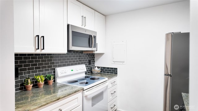 kitchen featuring dark stone counters, appliances with stainless steel finishes, white cabinetry, and tasteful backsplash