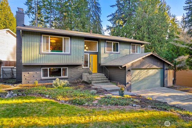 split foyer home featuring a garage, driveway, brick siding, and a chimney