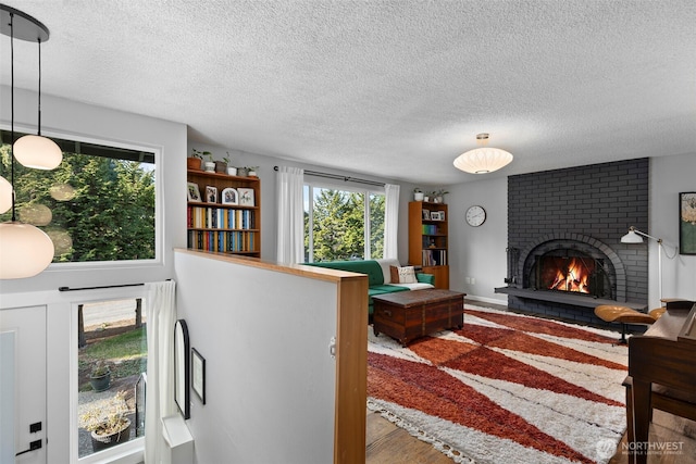 living room with a textured ceiling, a brick fireplace, and wood finished floors