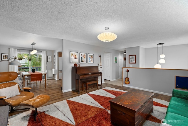 living room featuring a textured ceiling, baseboards, and wood finished floors