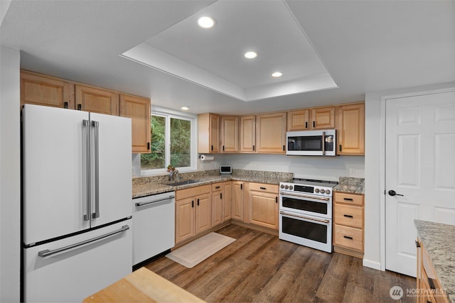 kitchen with dishwashing machine, double oven range, a tray ceiling, freestanding refrigerator, and stainless steel microwave