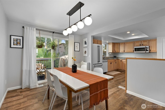 dining area with a raised ceiling, recessed lighting, baseboards, and dark wood-style flooring