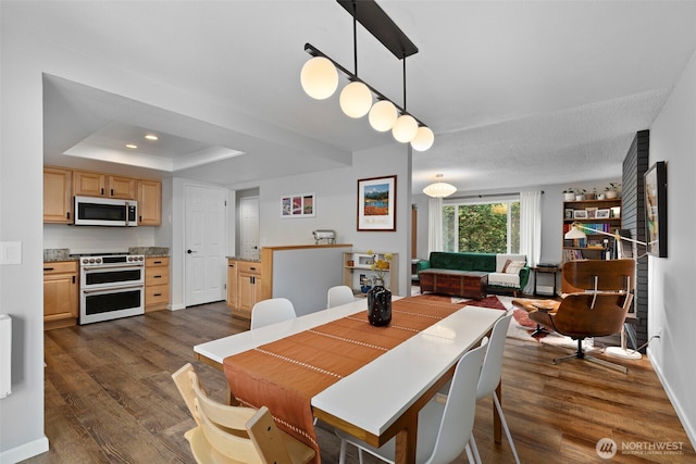 dining area featuring a raised ceiling, recessed lighting, baseboards, and dark wood-style flooring