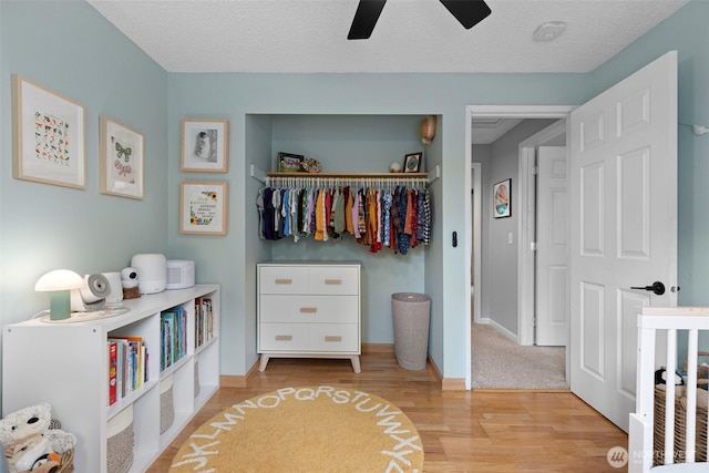 bedroom with a closet, baseboards, a textured ceiling, and wood finished floors