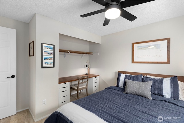 carpeted bedroom with baseboards, a ceiling fan, a closet, and a textured ceiling