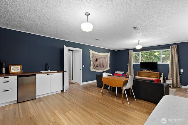 dining area with visible vents, baseboards, a textured ceiling, and light wood-style flooring