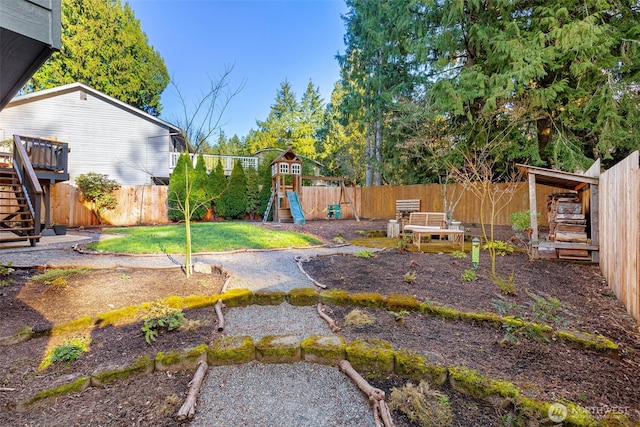 view of yard with a fenced backyard, stairs, and a playground