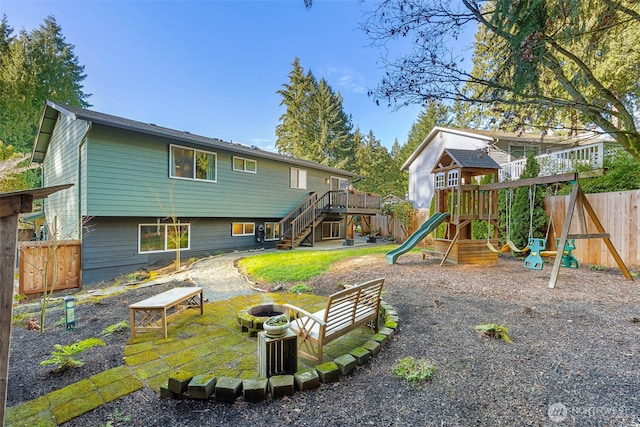 rear view of property with stairs, a playground, fence, and an outdoor fire pit