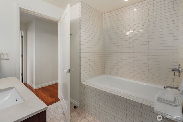 full bathroom with tiled shower / bath combo, wood finished floors, vanity, and baseboards