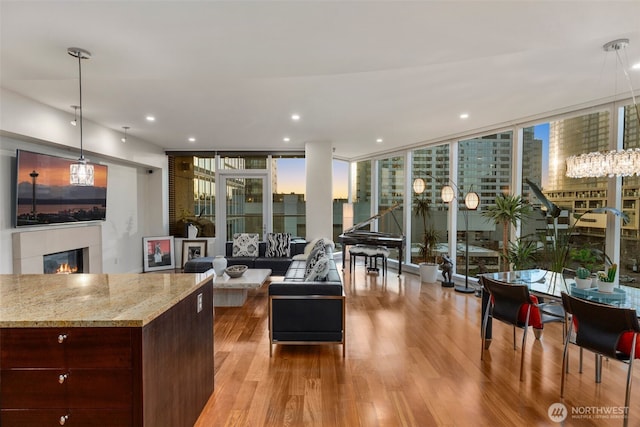 interior space featuring recessed lighting, a wall of windows, wood finished floors, and a glass covered fireplace