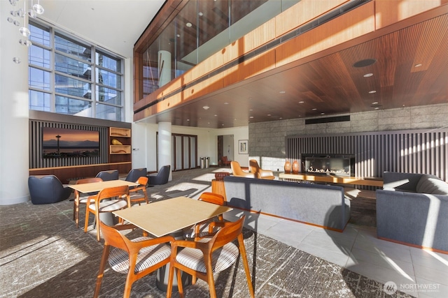 dining area with a glass covered fireplace and a towering ceiling