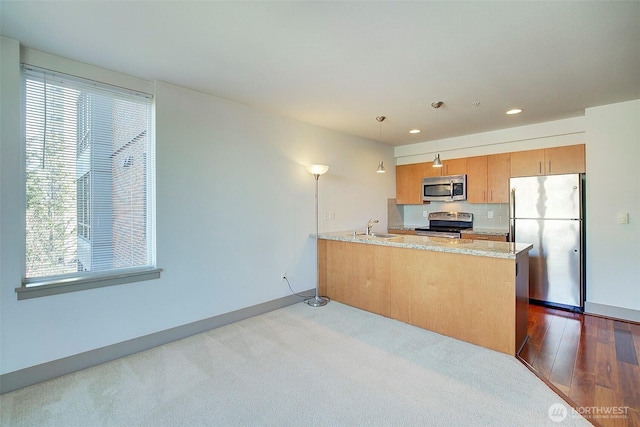 kitchen with a peninsula, plenty of natural light, appliances with stainless steel finishes, and a sink