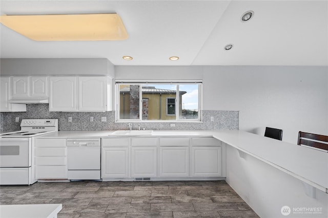 kitchen with white appliances, a sink, white cabinets, light countertops, and decorative backsplash