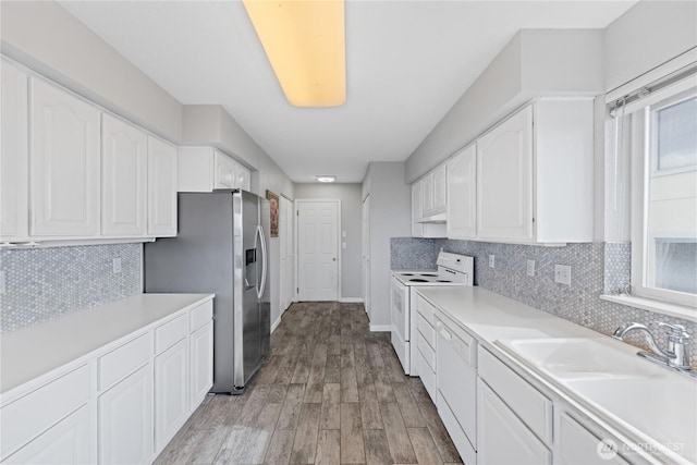 kitchen with white appliances, light wood finished floors, white cabinets, light countertops, and a sink