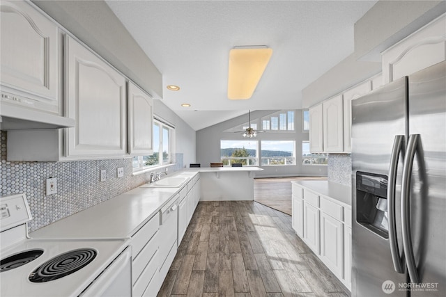 kitchen with white cabinets, stainless steel fridge, decorative backsplash, and white range with electric cooktop