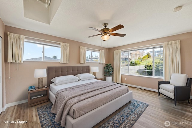 bedroom with baseboards, multiple windows, visible vents, and light wood finished floors