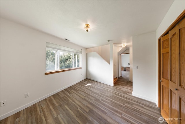 unfurnished room with visible vents, baseboards, and wood finished floors