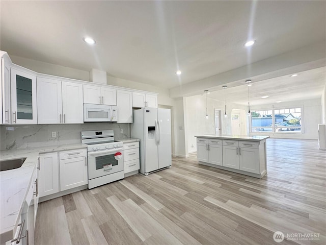 kitchen with decorative backsplash, light wood-style floors, white cabinetry, light stone countertops, and white appliances