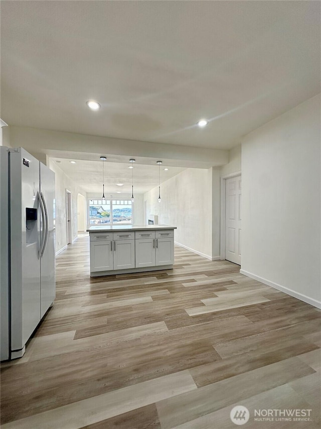 kitchen with light wood finished floors, recessed lighting, refrigerator with ice dispenser, and pendant lighting