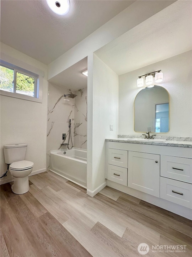 full bathroom featuring toilet, wood finished floors, vanity, baseboards, and  shower combination