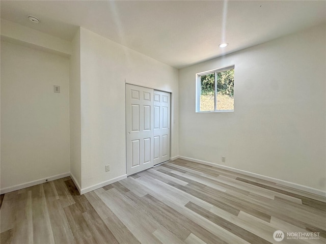 unfurnished bedroom with recessed lighting, a closet, light wood-style flooring, and baseboards