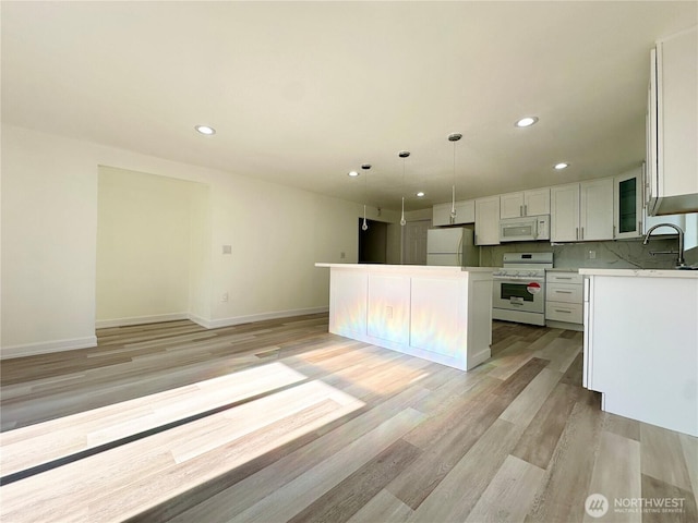 kitchen featuring white appliances, light countertops, light wood finished floors, and white cabinetry