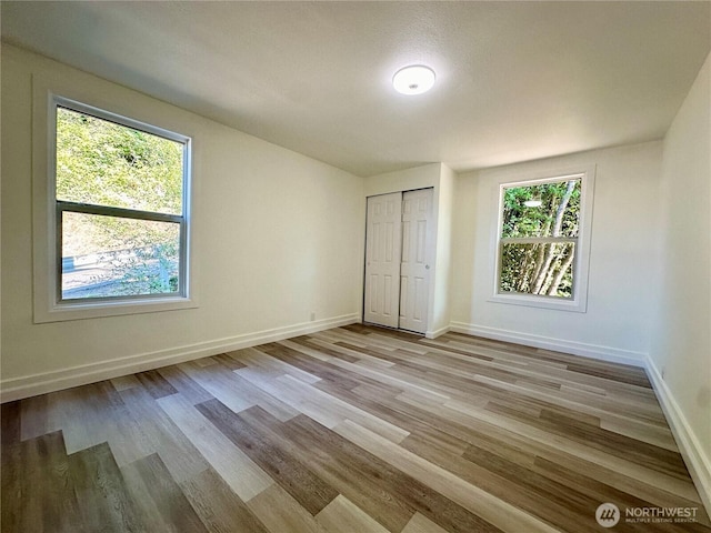 unfurnished bedroom with a closet, baseboards, and wood finished floors