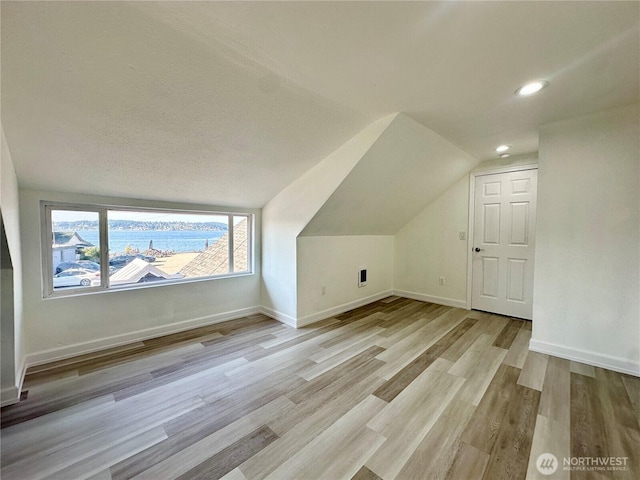 additional living space featuring lofted ceiling, light wood finished floors, baseboards, and recessed lighting