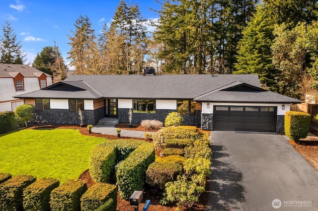 view of front of house featuring stone siding, a front lawn, an attached garage, and driveway