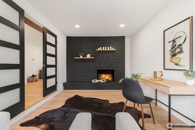 home office featuring a fireplace, wood finished floors, and recessed lighting