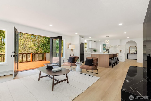 living room with light wood-type flooring, arched walkways, and recessed lighting