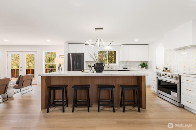 kitchen with a center island, stainless steel electric range oven, custom exhaust hood, white cabinetry, and black fridge