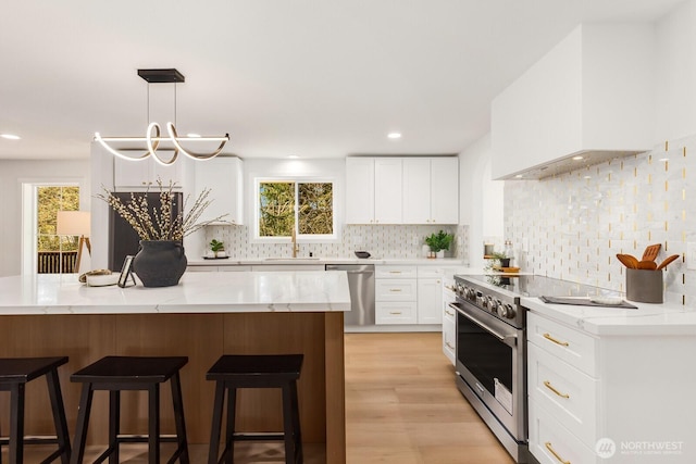 kitchen featuring appliances with stainless steel finishes, a breakfast bar area, custom exhaust hood, and light stone counters