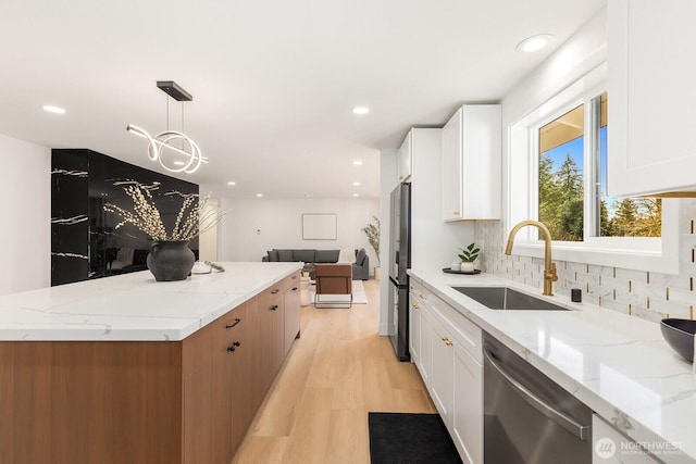 kitchen featuring appliances with stainless steel finishes, a sink, light stone countertops, and white cabinets