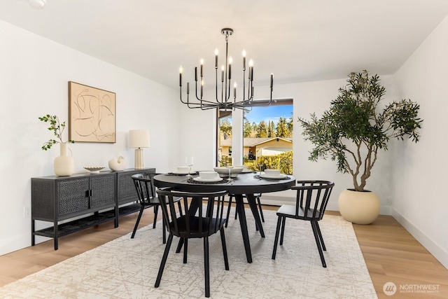 dining room featuring a notable chandelier, baseboards, and wood finished floors